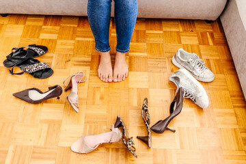 Cropped shot of an unrecognizable woman trying on various shoes at home. Cropped shot of a woman trying on different pairs of shoes. Unrecognizable shopper fitting on new shoes.