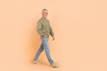 Fototapeta premium Full length photo of funky old grey hairdo man go wear eyewear pullover jeans sneakers isolated on beige background