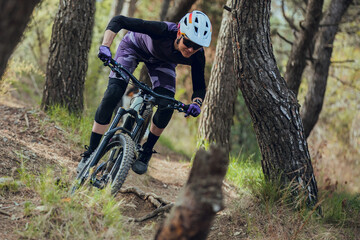 Close up of Woman mtb rider with australian shepherd dog riding mtb bike down trail in forest