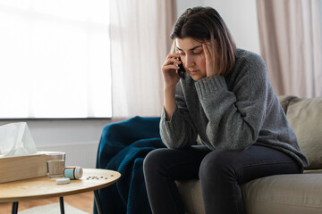 mental health, psychological help and depression concept - stressed woman with sedative medicine on table calling on phone at home - obrazy, fototapety, plakaty