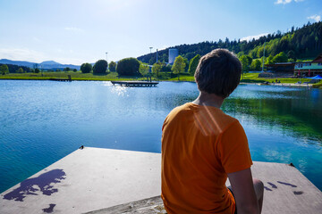 Guy teenager rests in the summer on vacation. Children swim in the lake.