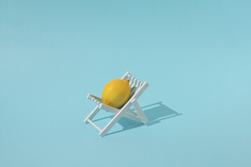 Fresh lemon on a beach chair with blue background. Colorful creative summer food concept.
