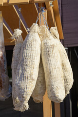 Salami sausages with white mold are hung on a string at a street food festival.