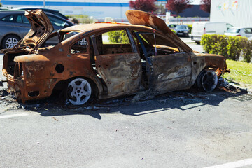 City car burned. Burnt out car with a small flame inside the engine