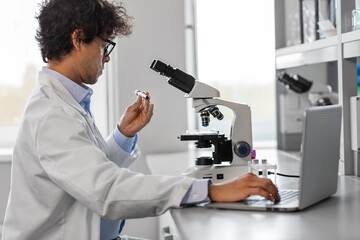 science research, work and people concept - male scientist with microscope working in laboratory
