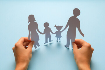 Fototapeta na wymiar Paper family in hand isolated on blue background
