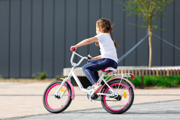Little girl on a bicycle in summer park.