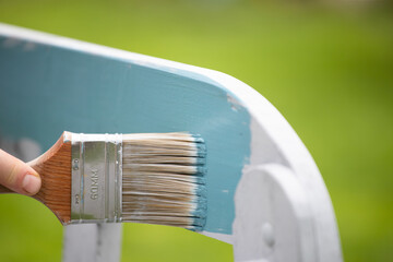 Close up paintbrush in hand and painting on the wooden furiture