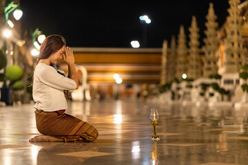 Young asia woman wearing traditional dress of Thailand to paying respect to Buddha statue at Wat...