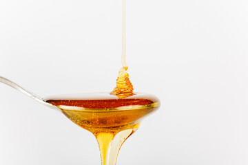 close up of honey being poured into a silver spoon, honey is a natural sweetener as a substitute...