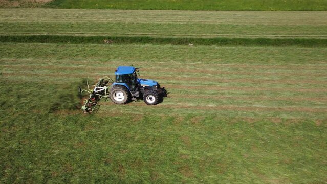Raking hay with a double wheel rake tractor on a sunny day aerial view	
