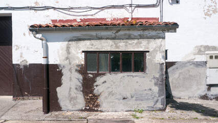 Ventana en pared marrón y blanca con manchas de cemento