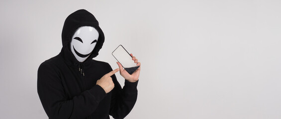 Anonymous hacker and face mask with smartphone in hand. Man in black hood shirt holding and using...