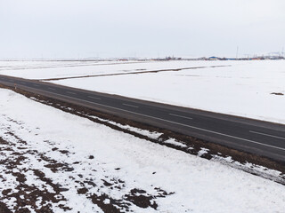 Aerial diagonal view of a road with one lane and snow in winter