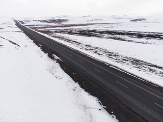 Aerial diagonal view of a road with one lane and snow in winter