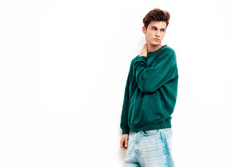 Portrait of handsome confident stylish hipster lambersexual model.Man dressed in green sweater and jeans. Fashion male posing in studio near white wall. Isolated