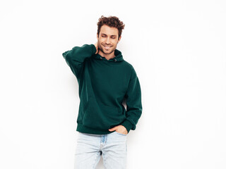 Handsome smiling hipster  model.Sexy unshaven man dressed in summer stylish green hoodie and jeans clothes. Fashion male with curly hairstyle posing in studio. Isolated on white
