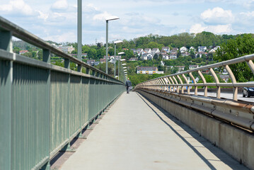 Pedestrian crossing on a highway bridge over a river in West Germany, you can see a man walking.