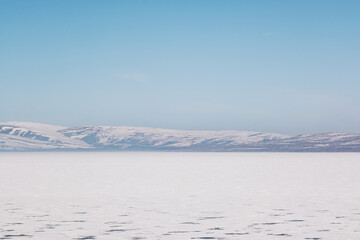 Landscape view of Frozen Cildir lake in Kars and snowy mountains with a blue sky in winter