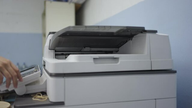 Hand of woman is using a photocopier to copy documents in workplace or office.