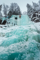 Climber on the top of the frozen waterfall, Norway.