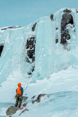 Climber on the top of the frozen waterfall, Norway.