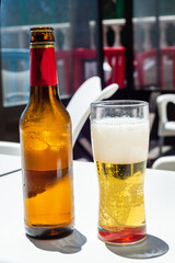 Bottle and glass of beer on a bar table outdoors