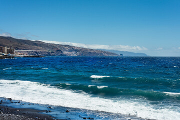 Waves reaching a black sand beach on a sunny day. Tenerife. Canary Islands.