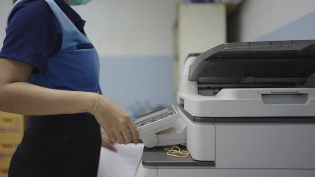 Hand of woman is using a photocopier to copy documents in workplace or office.