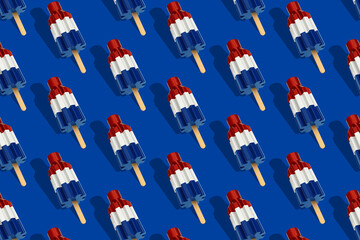 Trendy sunlight Summer pattern made with red white and blue bomb pop popsicle ice cream on blue background. Minimal summer concept for July 4th.