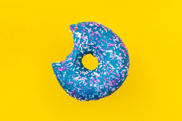 Bitten blue glazed donut with colorful sprinkles