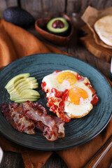Breakfast with fried eggs with tomato, bacon and avocado