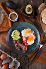 Breakfast with fried eggs with tomato, bacon and avocado