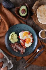 Breakfast with fried eggs with tomato, bacon and avocado