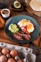 Breakfast with fried eggs with tomato, bacon and avocado