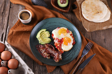 Breakfast with fried eggs with tomato, bacon and avocado