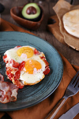 Breakfast with fried eggs with tomato, bacon and avocado