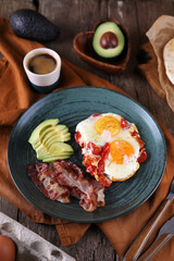 Breakfast with fried eggs with tomato, bacon and avocado