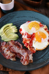 Breakfast with fried eggs with tomato, bacon and avocado