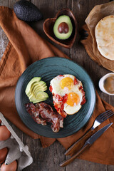Breakfast with fried eggs with tomato, bacon and avocado