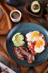 Breakfast with fried eggs with tomato, bacon and avocado