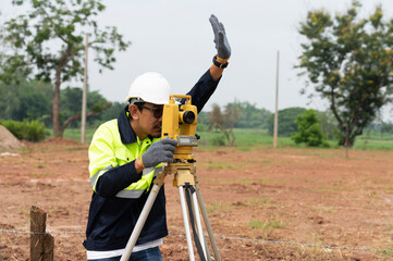 A young surveying engineer is measuring the level at a construction site. Surveyors certify...
