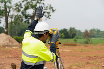 A young surveying engineer is measuring the level at a construction site. Surveyors certify...