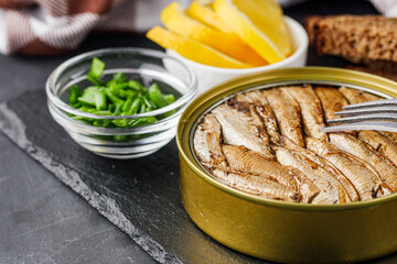 canned sprats in oil on a dark stone background