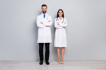 Full length body size view of two attractive cheery medics folded arms insurance isolated on grey...
