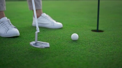 Golfer legs hitting ball on green golf course. Sport player teeing score outside