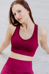 beautiful girl in burgundy tracksuit in fitness room. cosmetics for athletes.