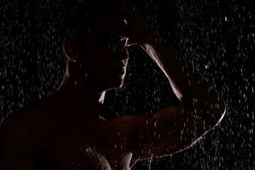 Fototapeta na wymiar silhouette of man under falling water drops on black background.