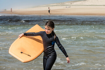 pretty little girl enjoying surfing the waves with a bodyboard during her vacation - 507071066