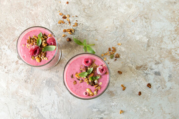 glasses with raspberry smoothie with granola on light table